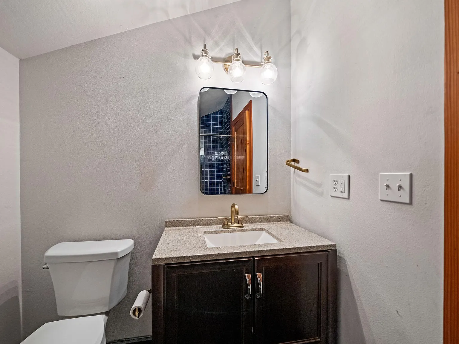 A bathroom vanity with a dark wood cabinet and antler-style light fixture