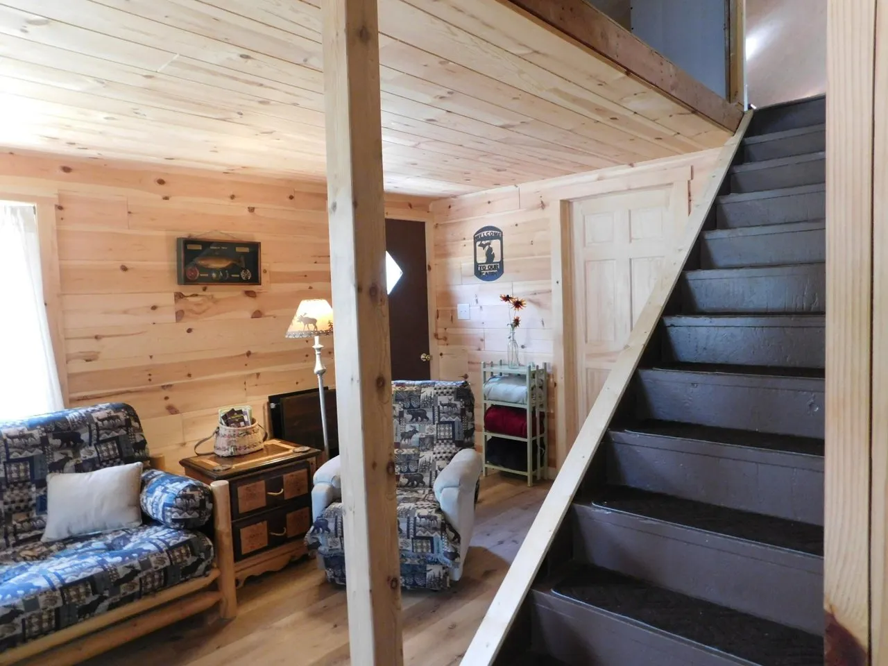 The living room with the stairs to the loft and knotty pine walls