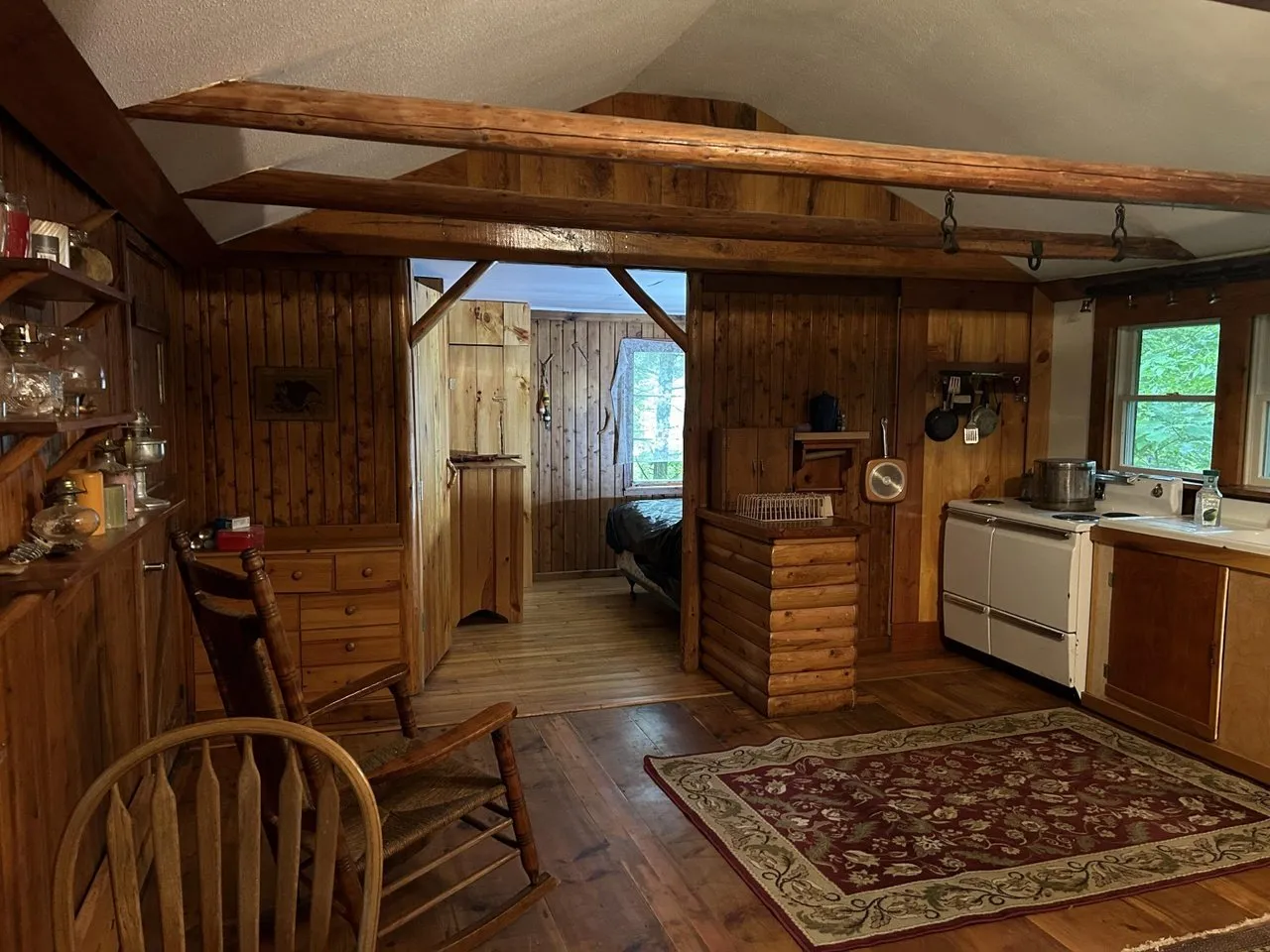 The kitchen end of the main room with wood cabinets and a window over the counter