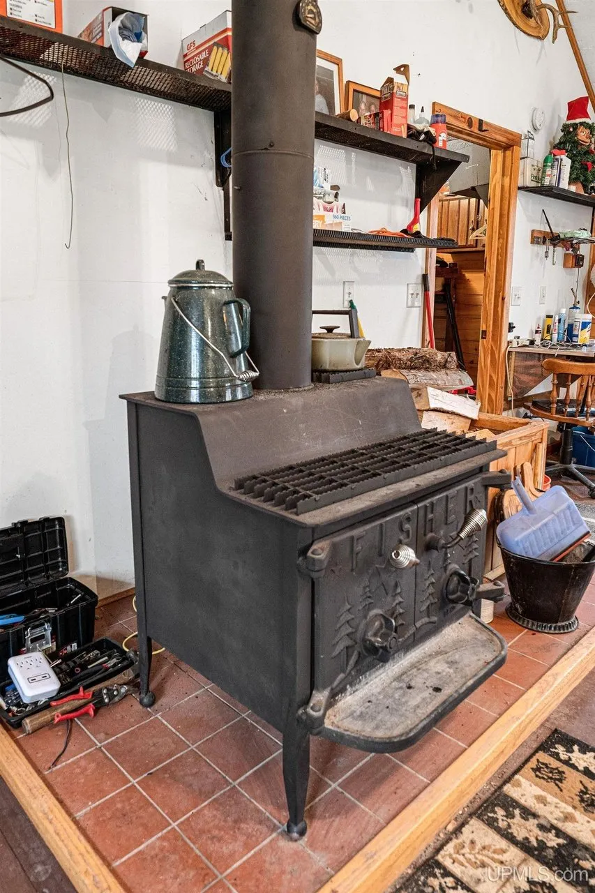 The wood-burning stove on its tiled hearth against the white wall