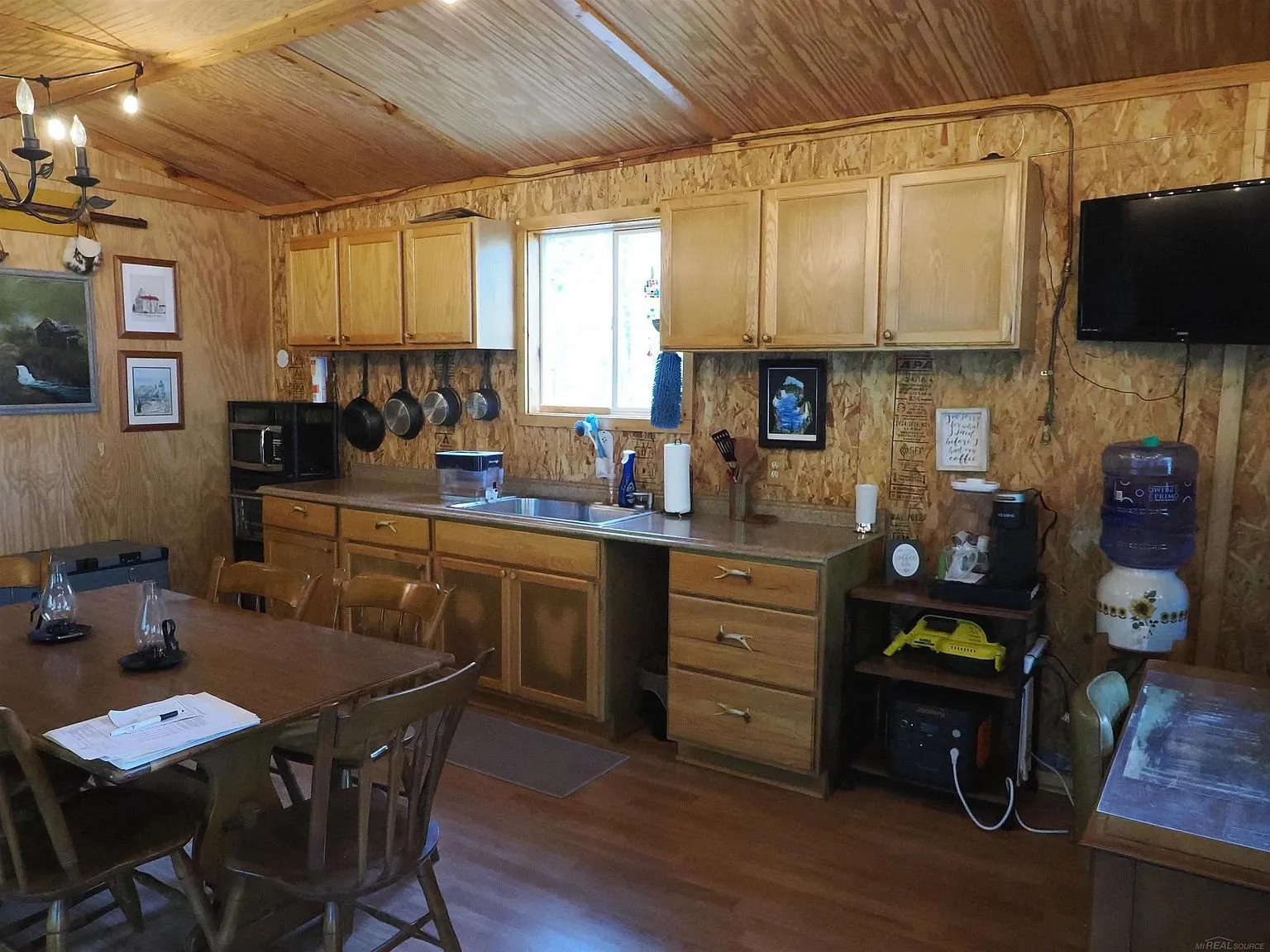 The kitchen with the oak cabinets, the sink and the pans on the wall