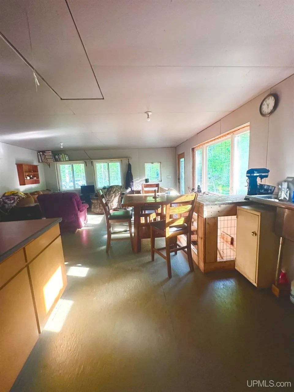 The kitchen and dining area with the table, the cabinets and the row of windows