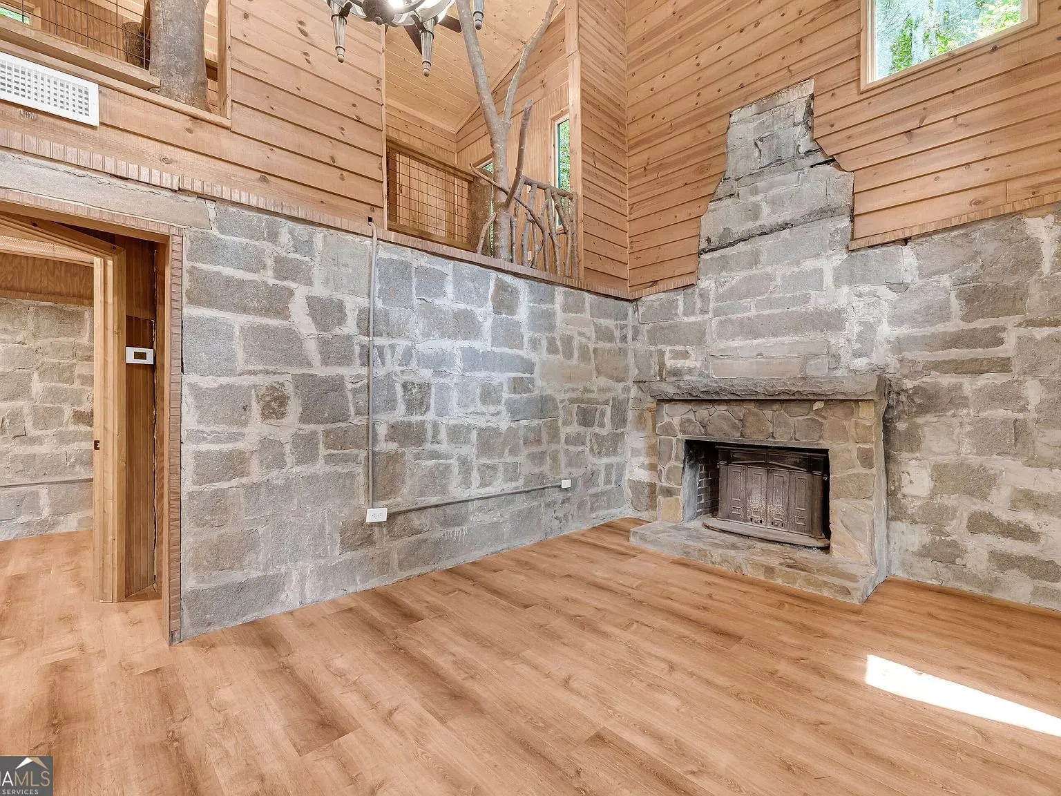 The stone fireplace rising to the vaulted ceiling in the main living space