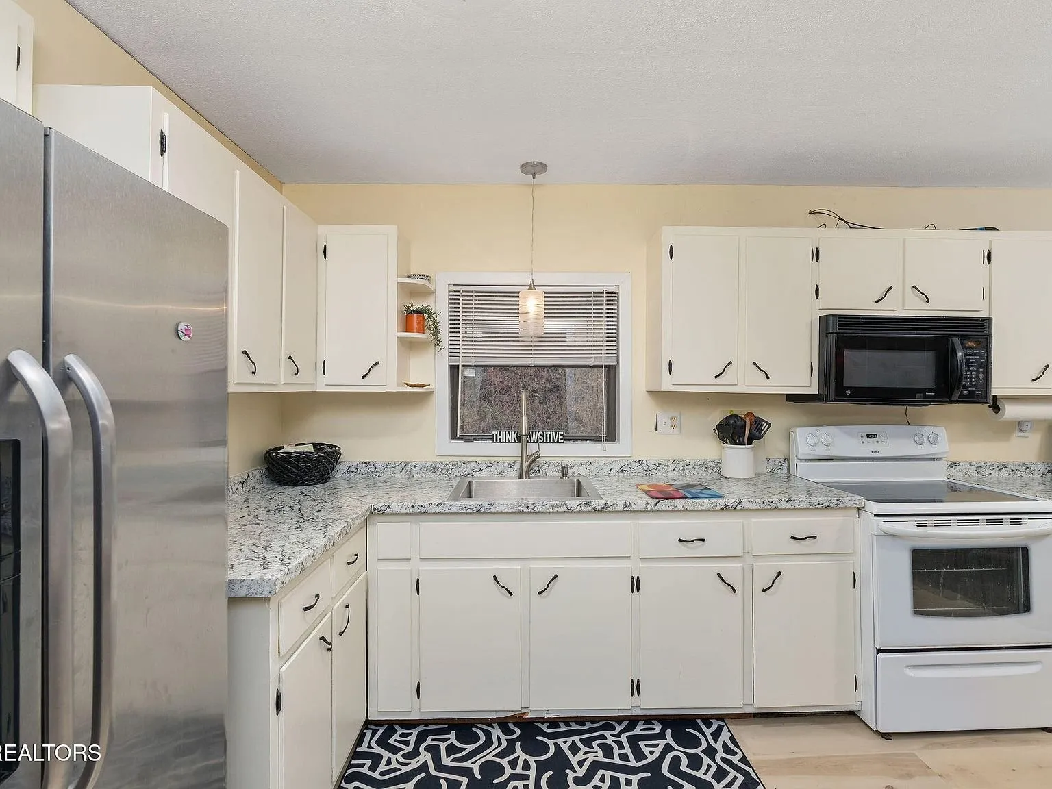 The kitchen counter and cabinets along the window wall