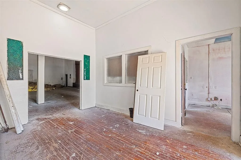 The front rooms with the doors off their hinges and the hardwood floor