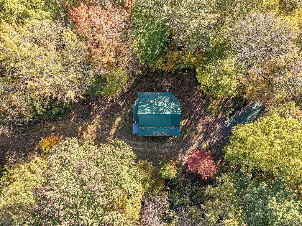 A second aerial view of the cabin and nearby storage shed among the trees