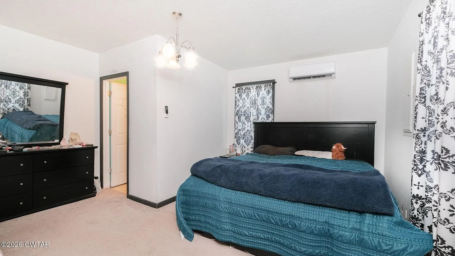 The main floor bedroom with a bed, dresser and a mini-split head