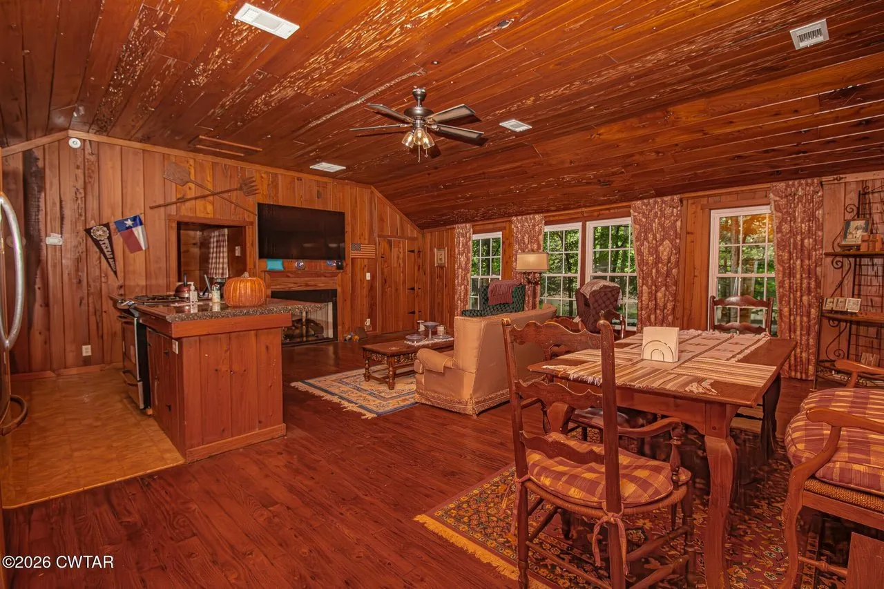 The great room from the kitchen end, dining table and windows to the woods