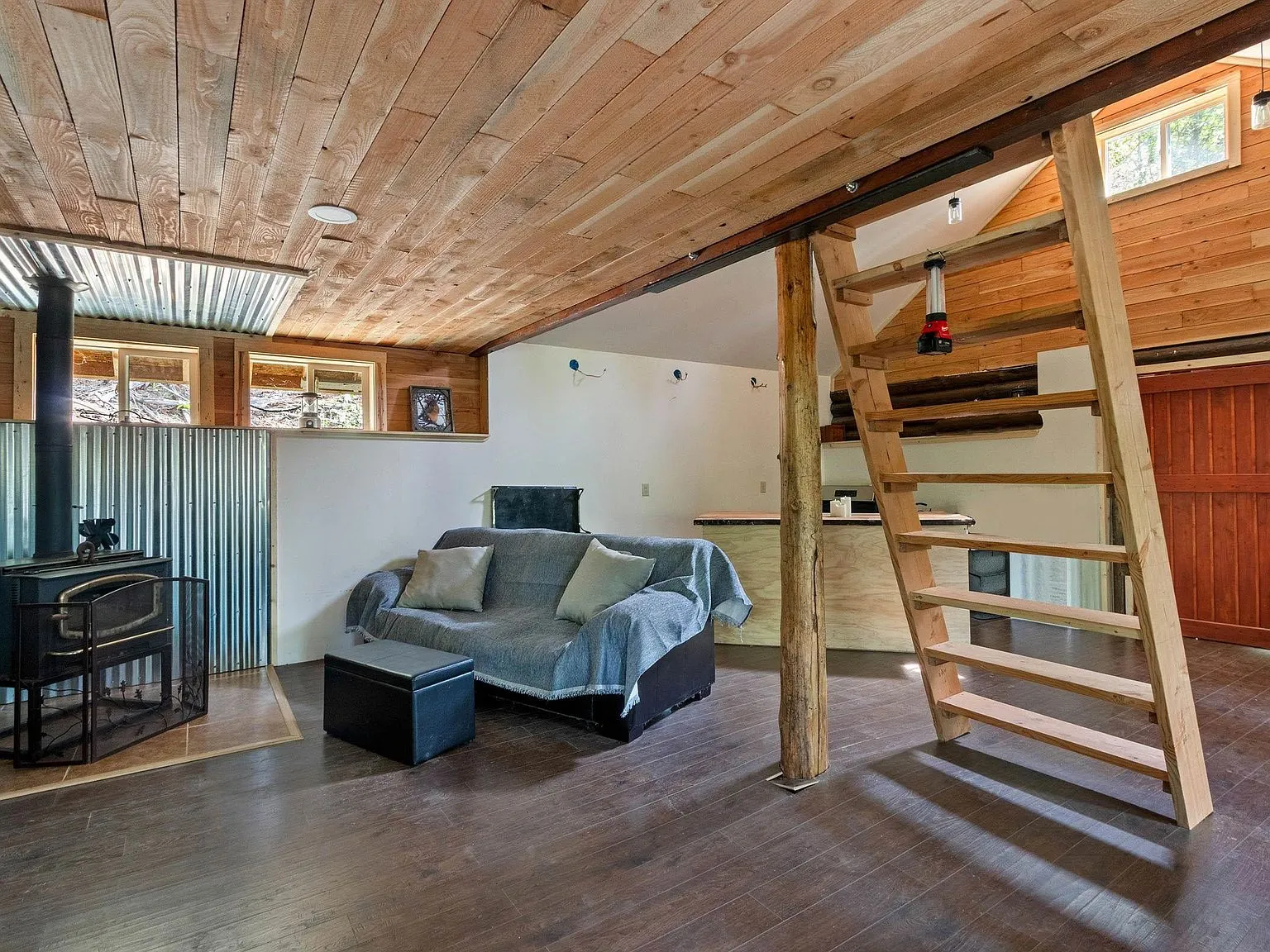 A wood ladder leading up to a loft sleeping area above the living room