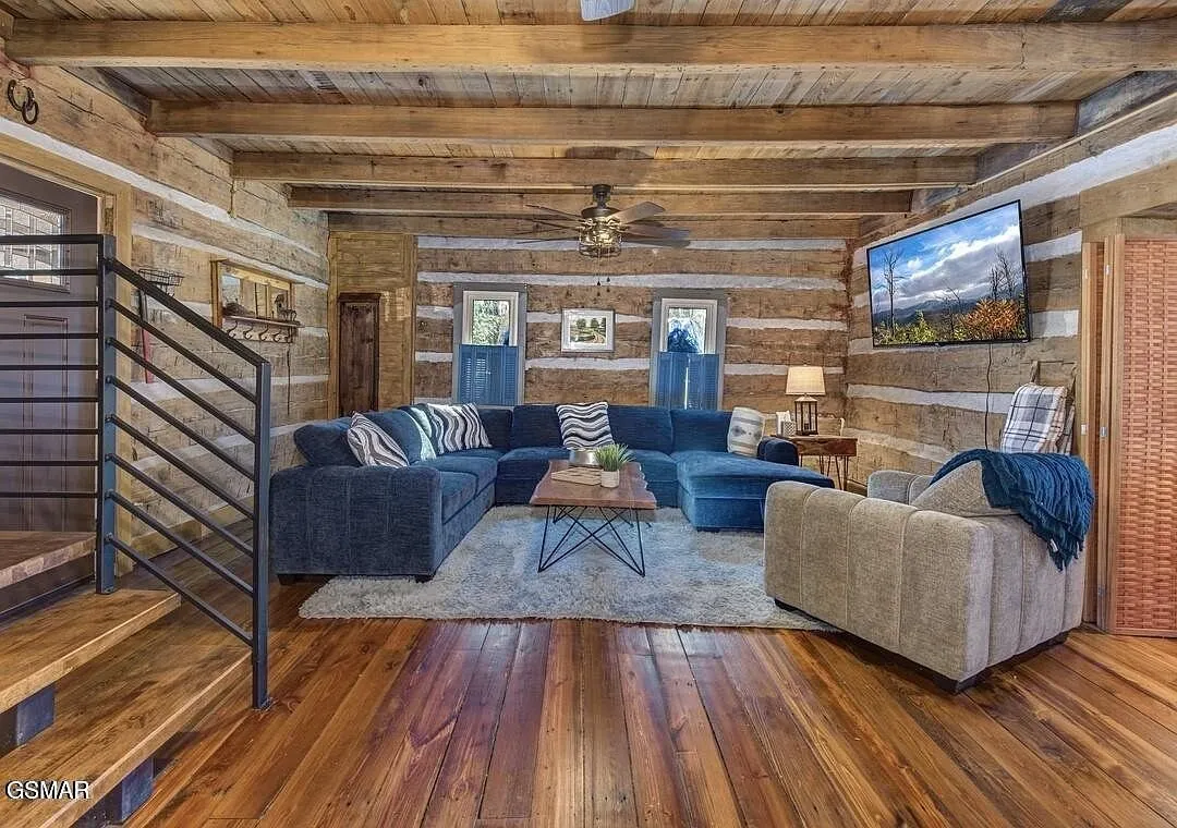 The living room with sectional seating, wood floors and the metal stair rail