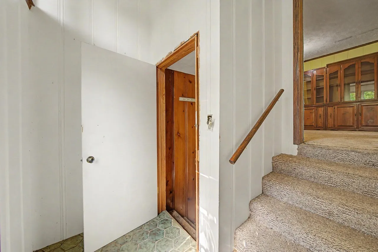 The entry with a wood door and the stairs to the upper floor