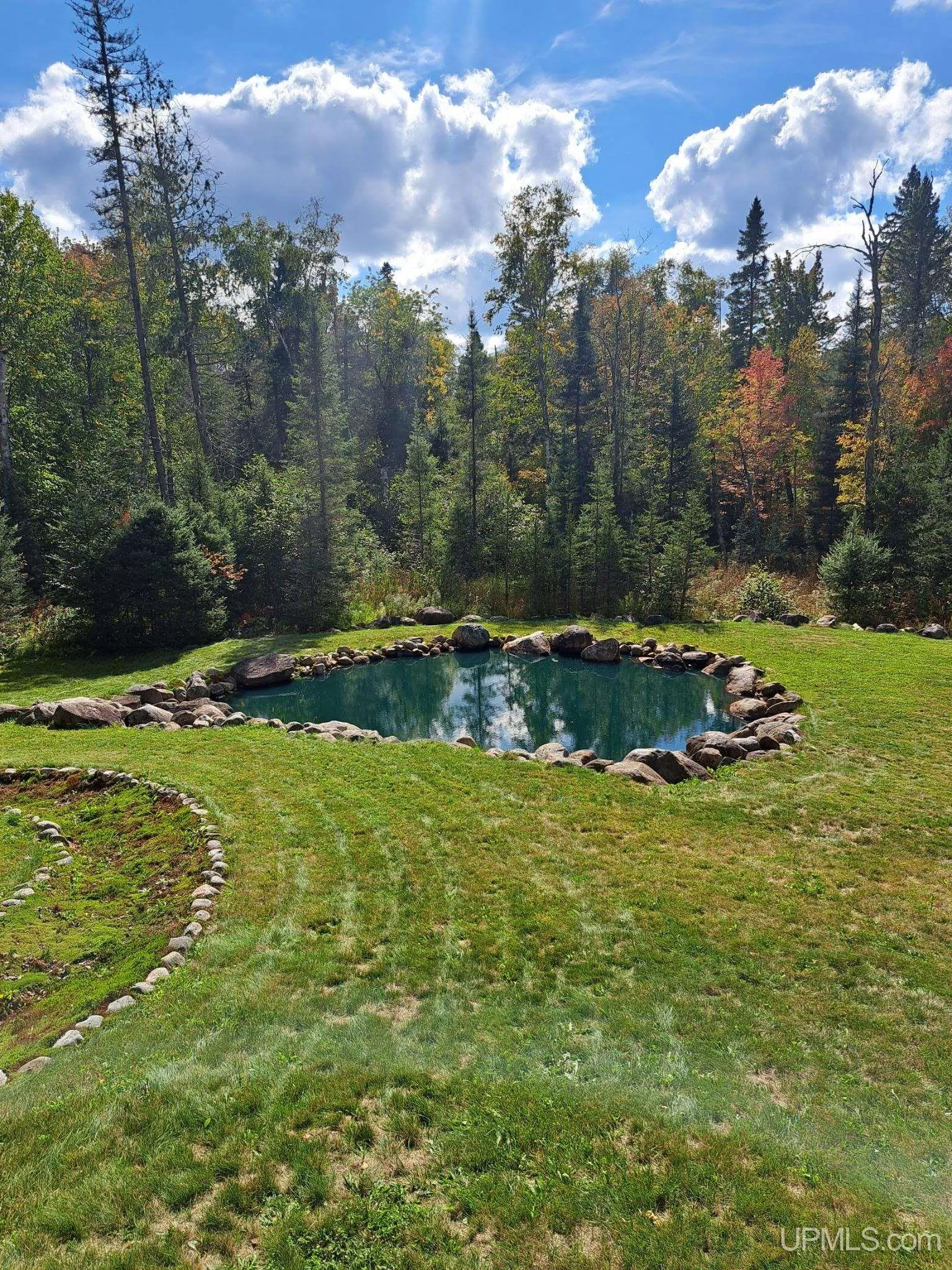 The pond from its bank, stone edging and the lawn around it