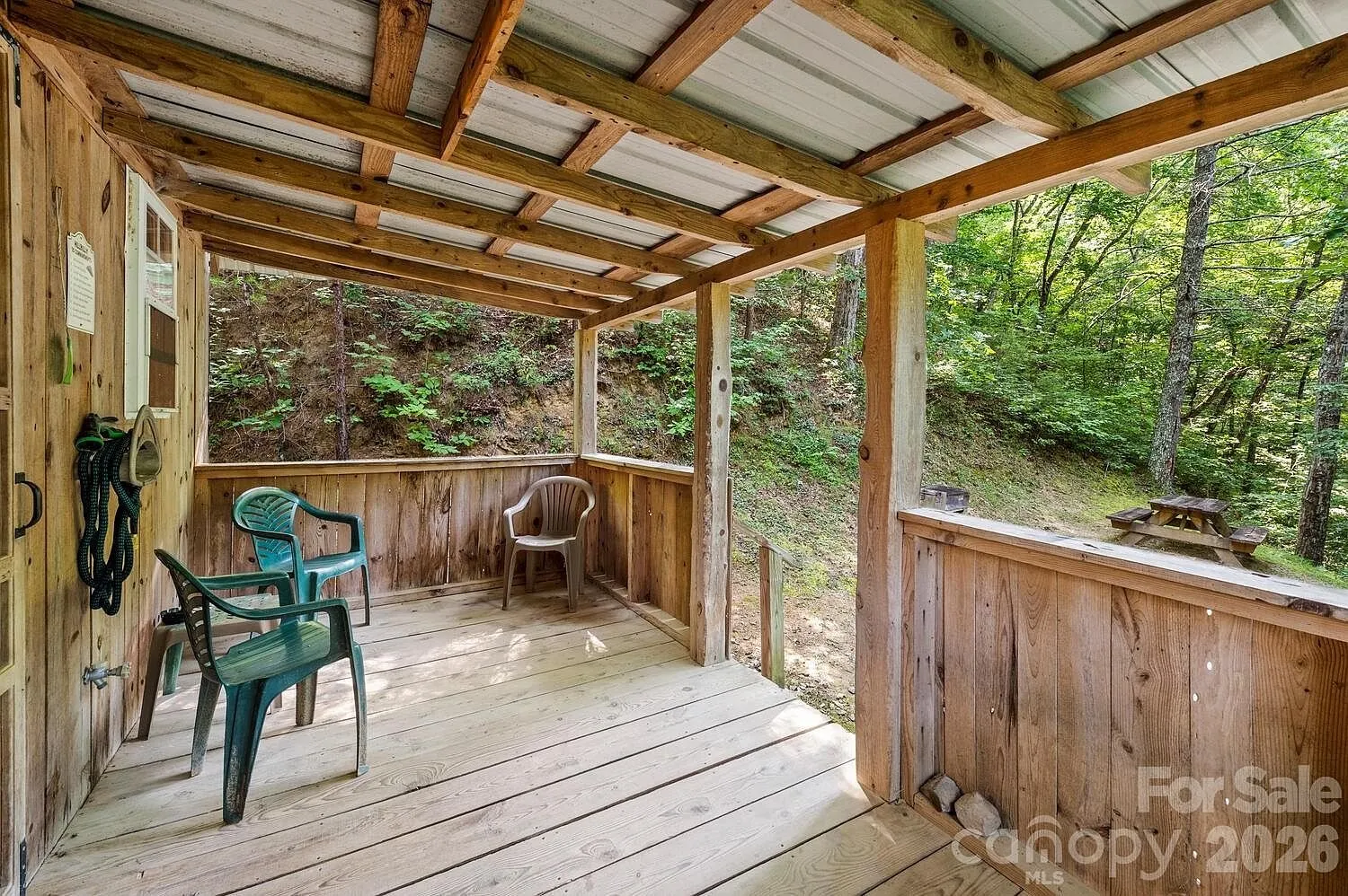 The covered porch with the chairs and the wooded slope beyond