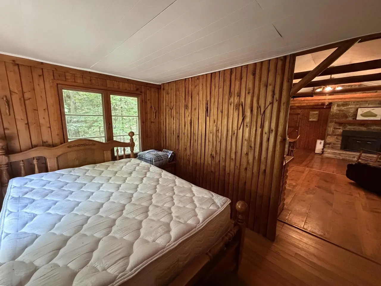 A bedroom in the spruce cabin, wood walls and a window to the trees