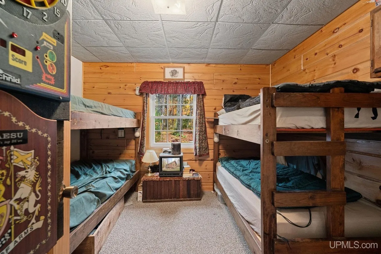 A bunk room with two sets of wooden bunks and a curtained window