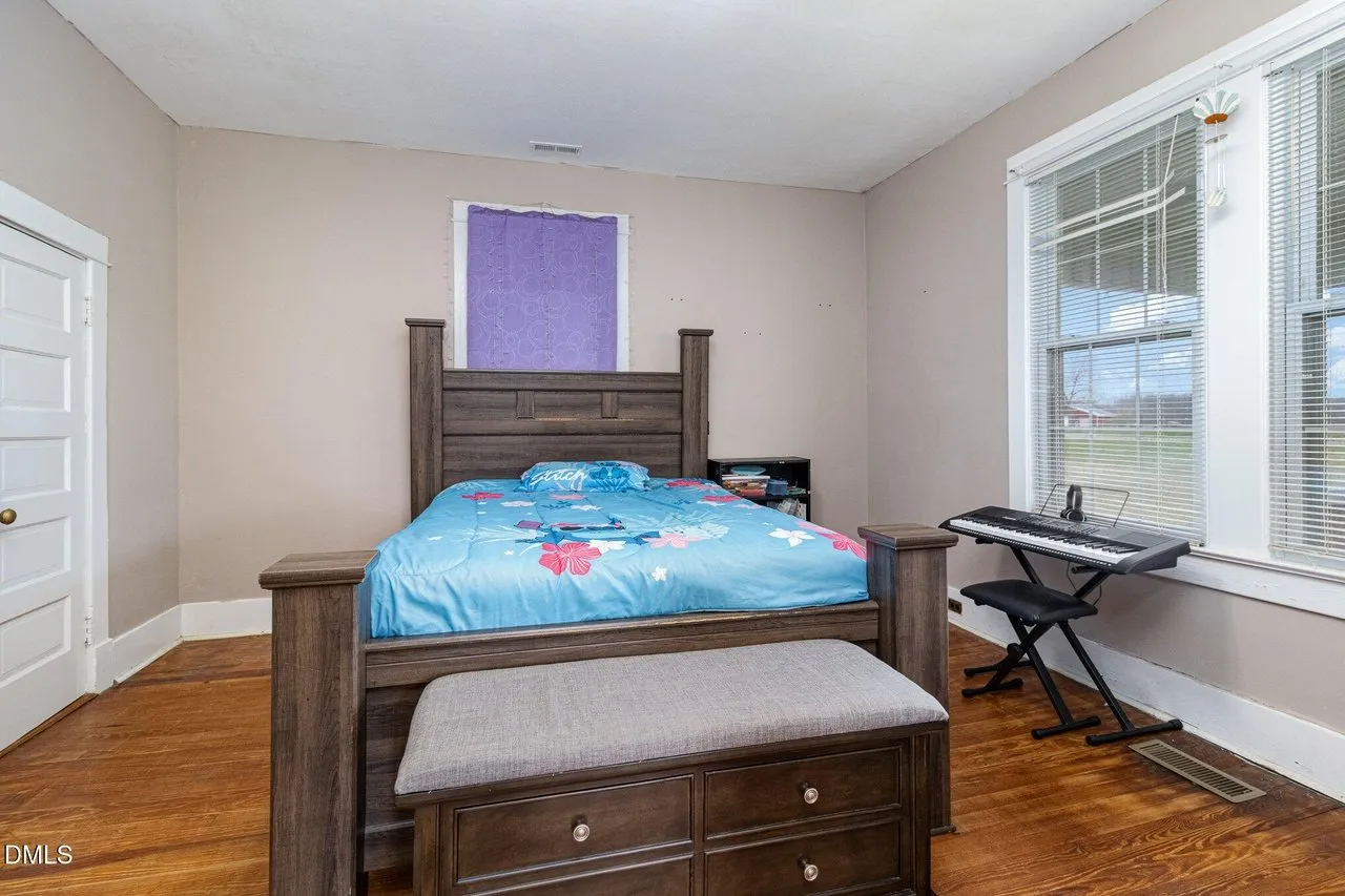 Bedroom with a wood bed frame, two windows and a ceiling fan