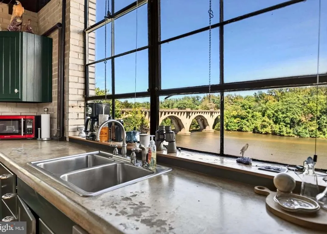 The kitchen sink and counter beneath a window framing the river and bridge