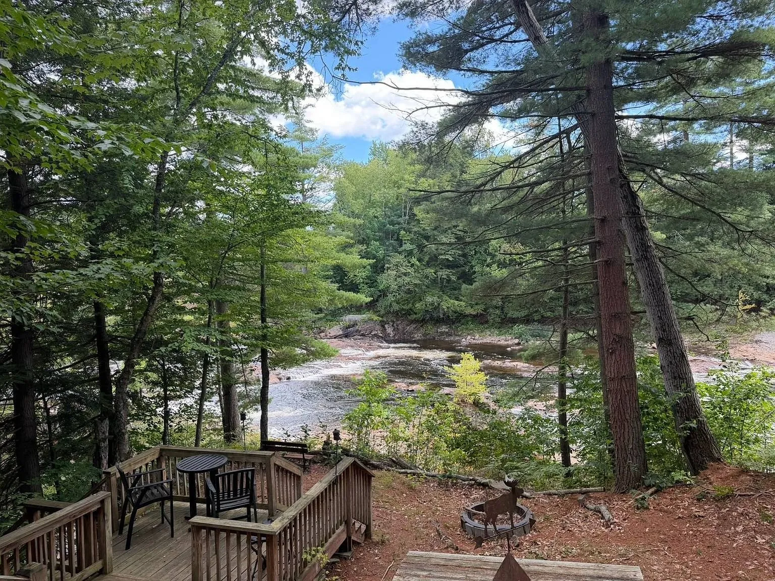 The lower deck with chairs and the fire pit above the river