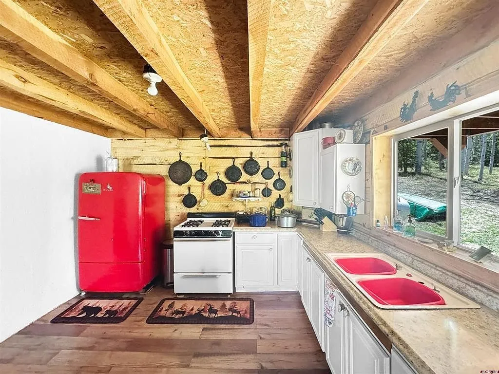 The kitchen counter with the sink under the window and the pans on the wall