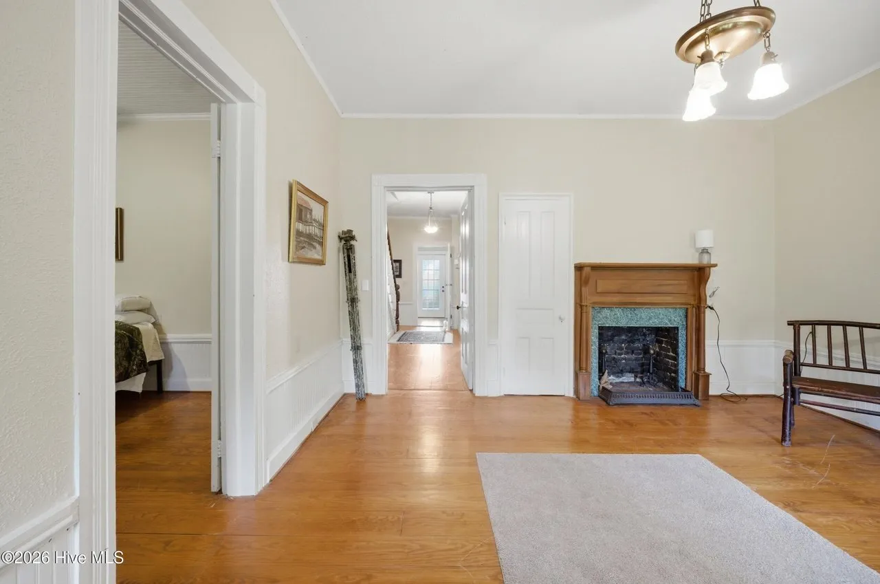 Entry hall with wood floors and a fireplace, looking through to the back of the house