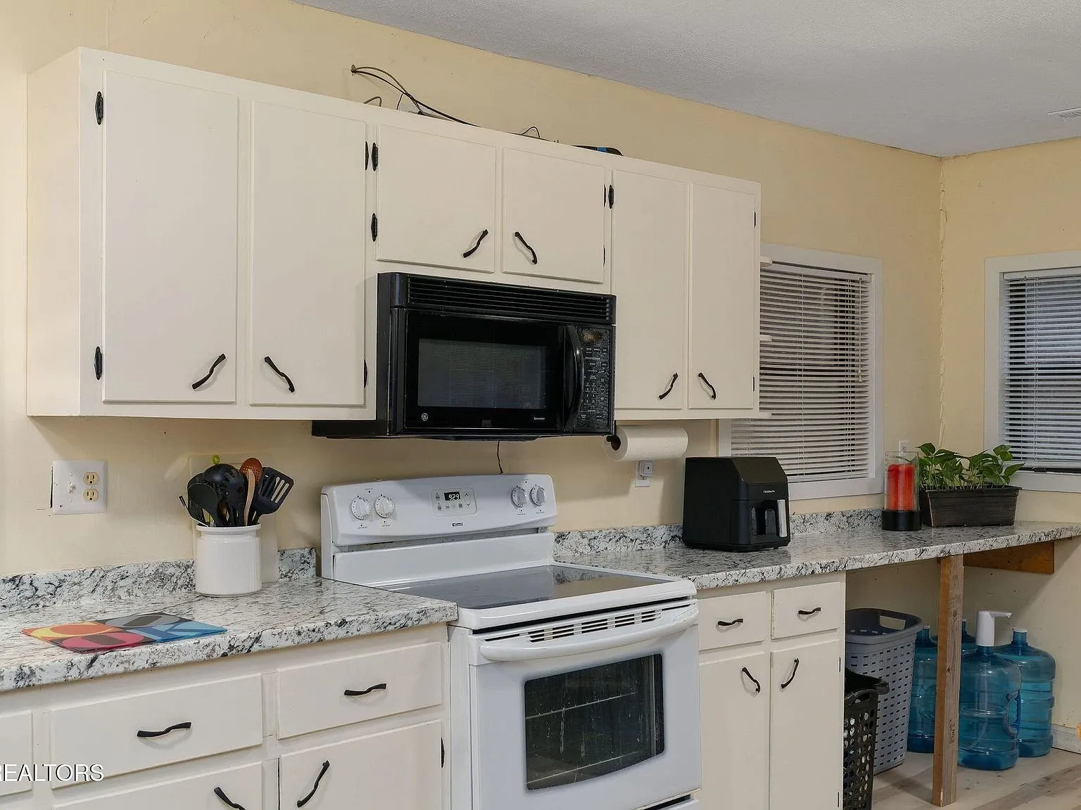 The kitchen seen from the dining table, refrigerator and range visible