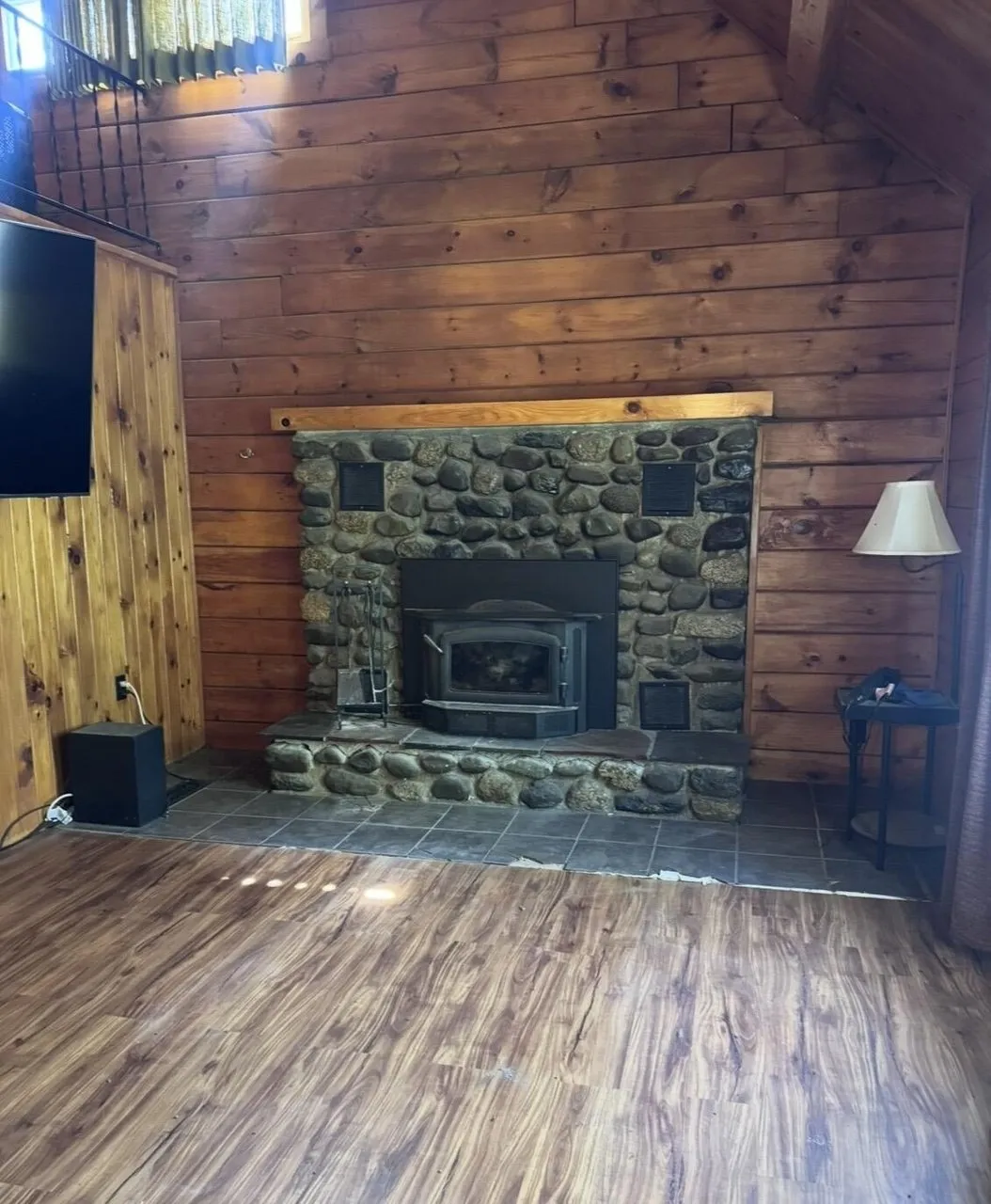 The stone fireplace with the wood insert, the mantel and the lamp