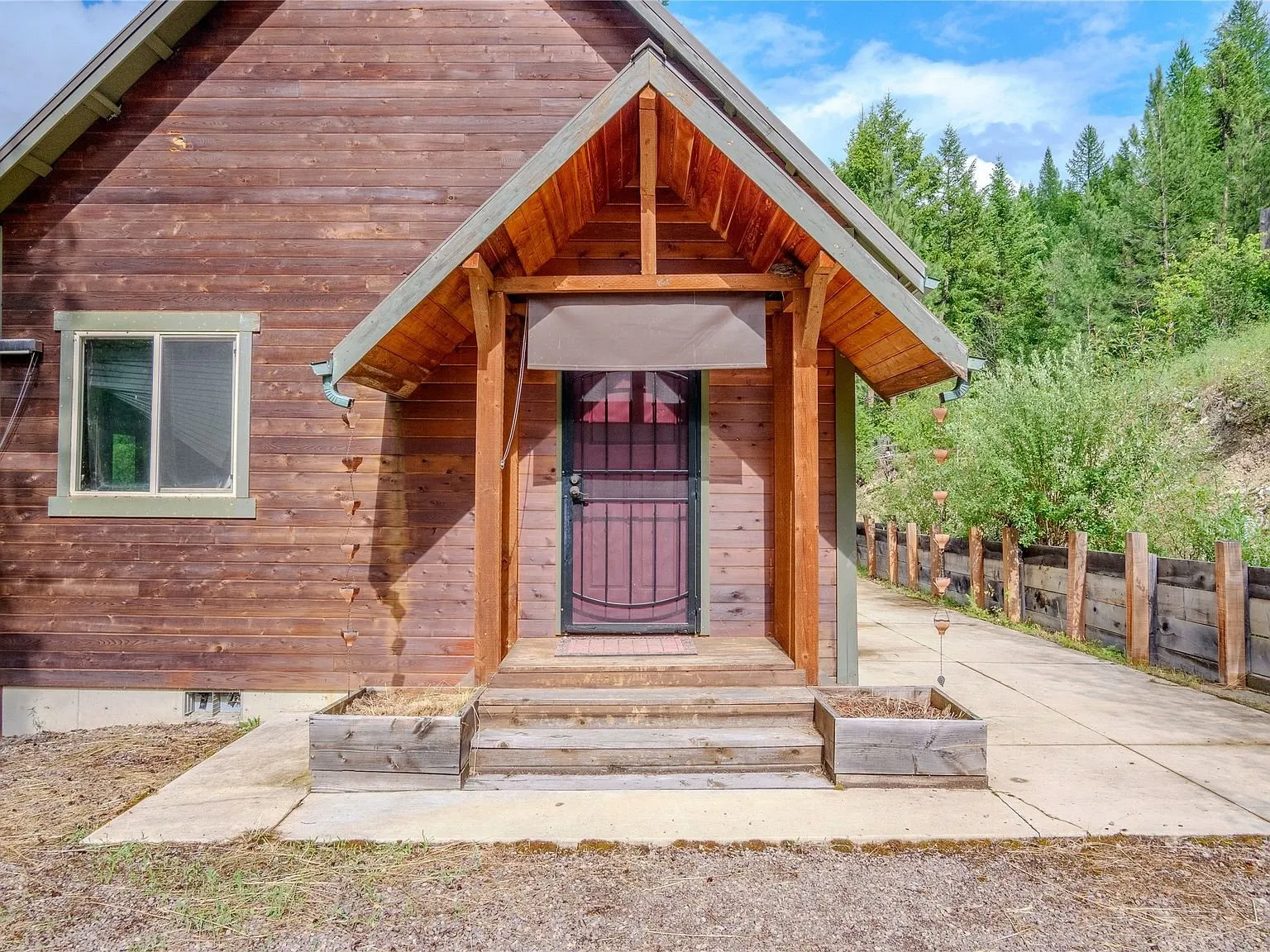 The cabin's covered front entry with a wrought iron security door