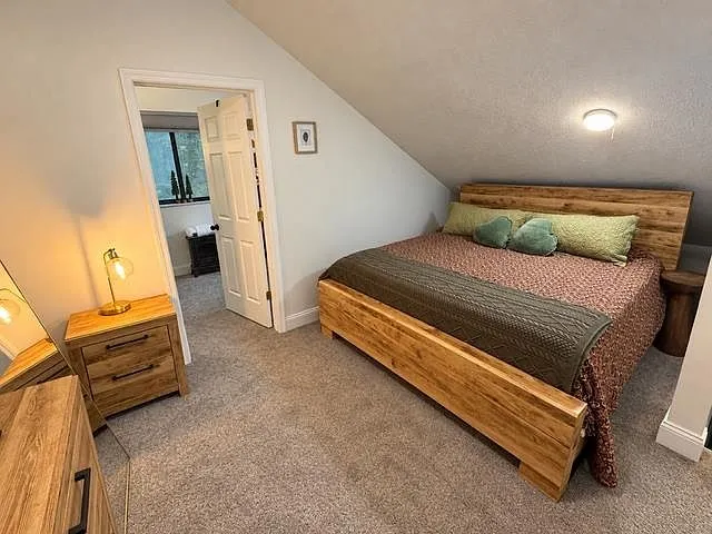 A carpeted bedroom with a wood bed frame and a wood West Virginia state cutout on the wall