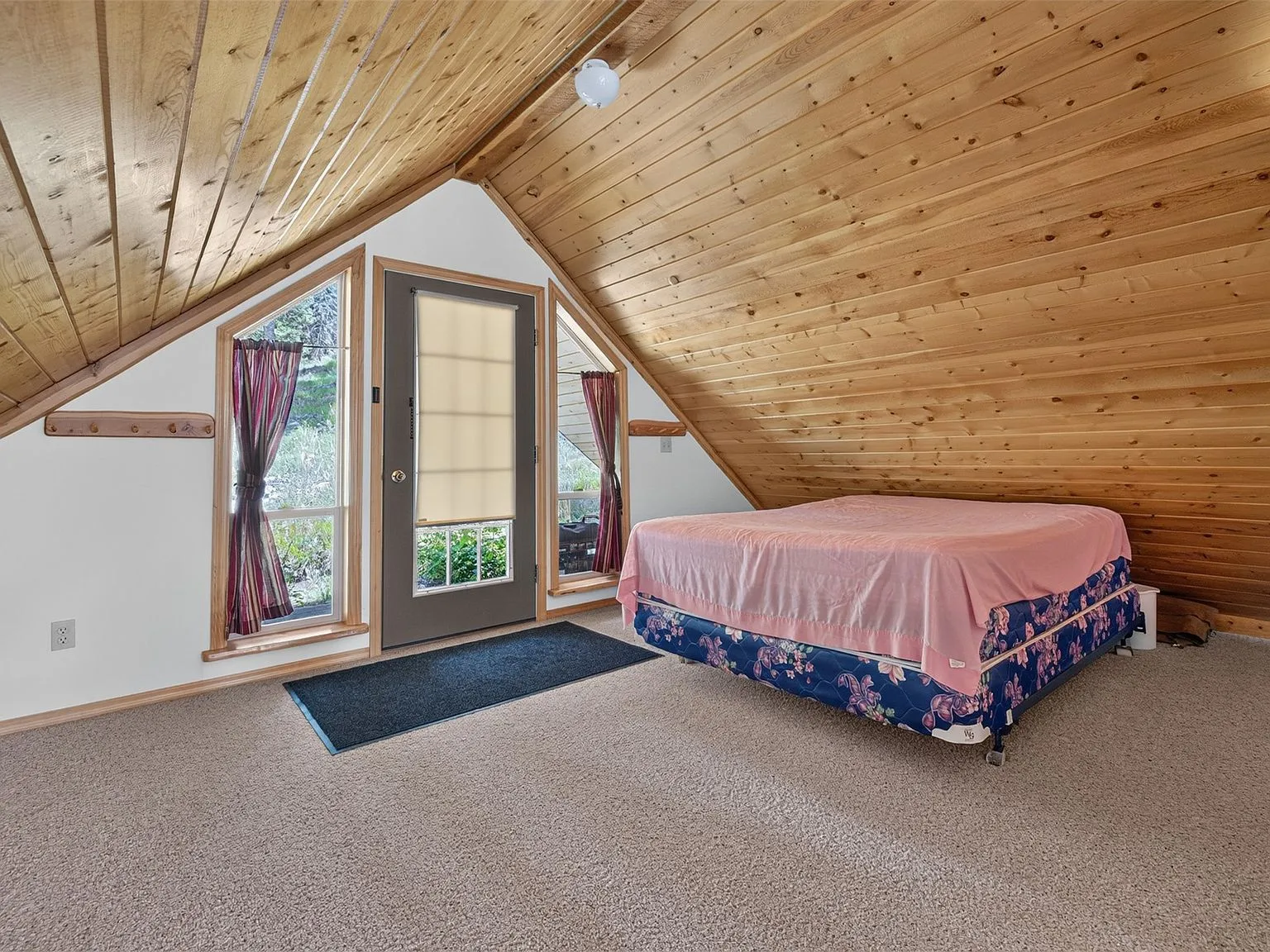 Two beds in the open loft space beneath the vaulted log ceiling