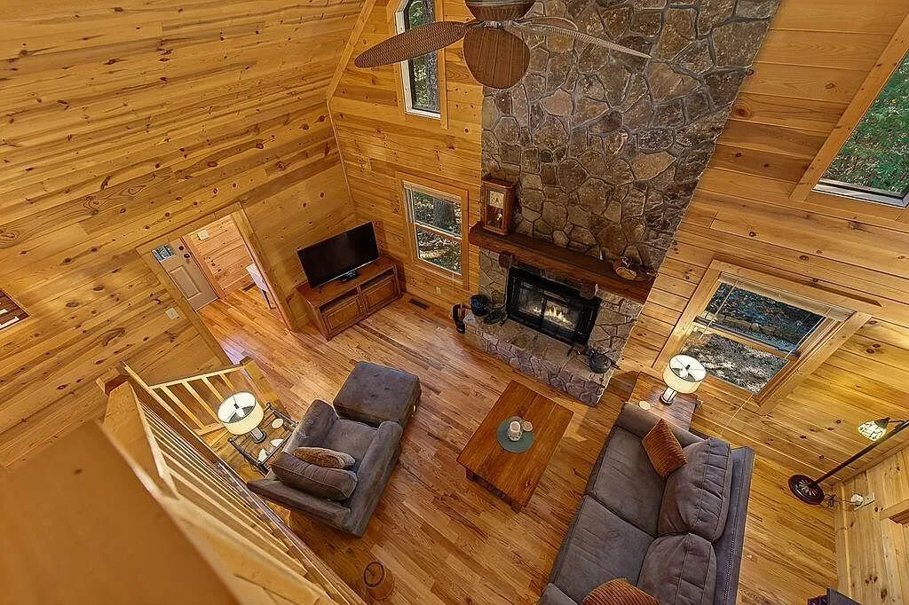 The vaulted great room from above, showing the stone fireplace and loft