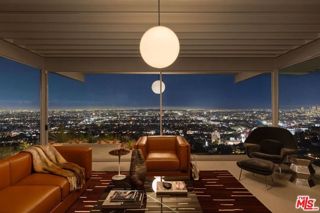 The living room at dusk with leather seating and a globe pendant under the steel roof