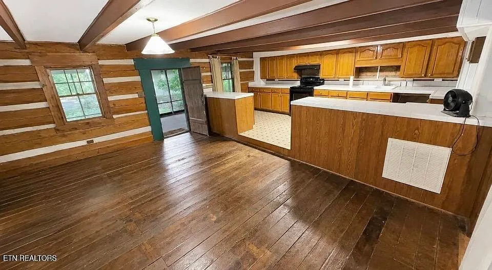 The kitchen with hand-hewn log walls and oak cabinets