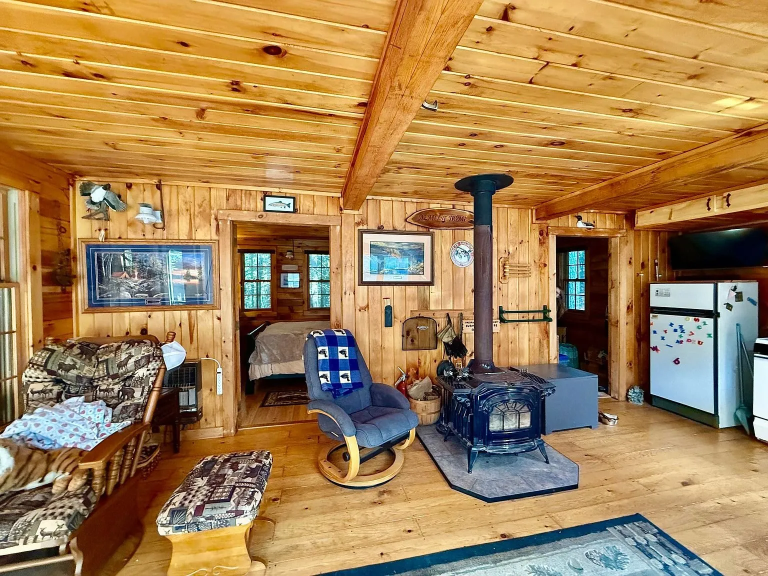 The living area with the wood stove, the pine walls and the refrigerator beyond