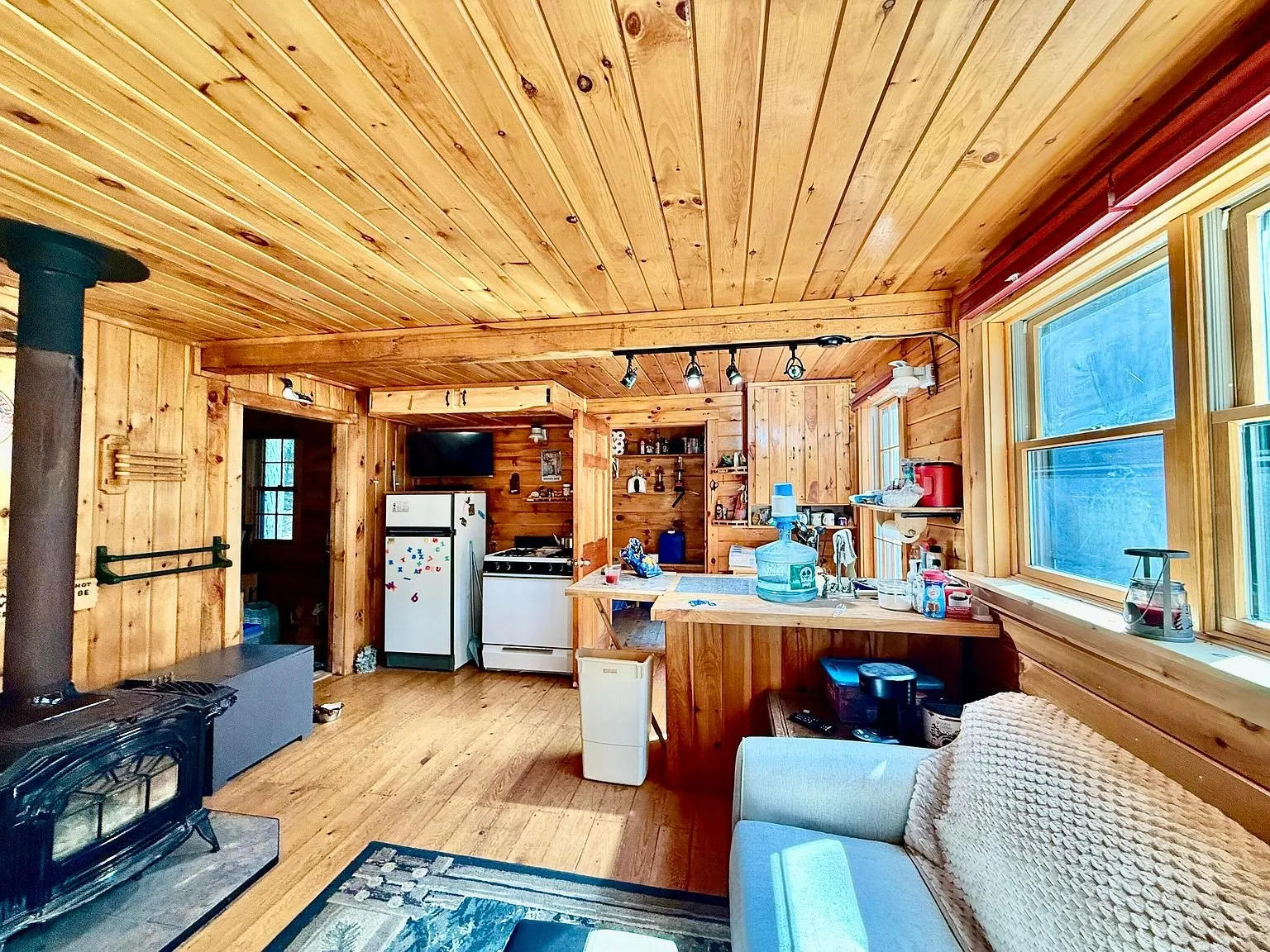 The open room with the wood stove, the kitchen and the windows