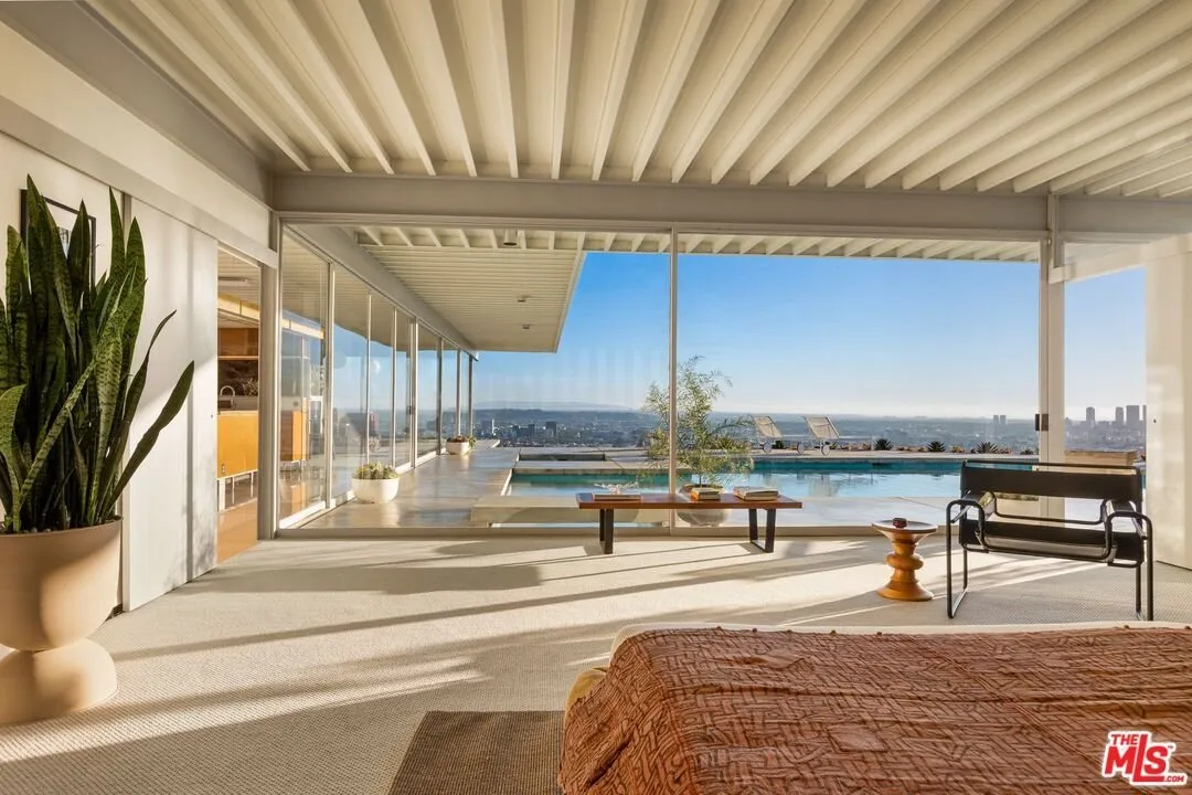 The living room in daylight, glass on two sides and the pool outside