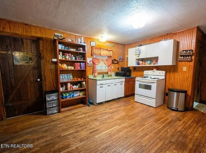 A pantry and kitchen nook with a stocked shelf, white cabinets and a range