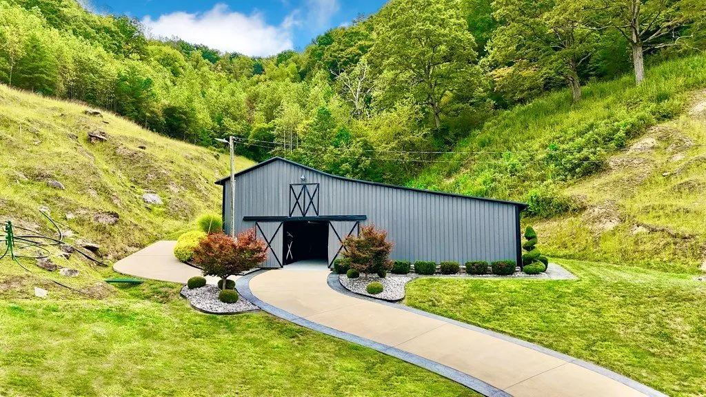 The two-story barn set against the hillside, drive curving past it