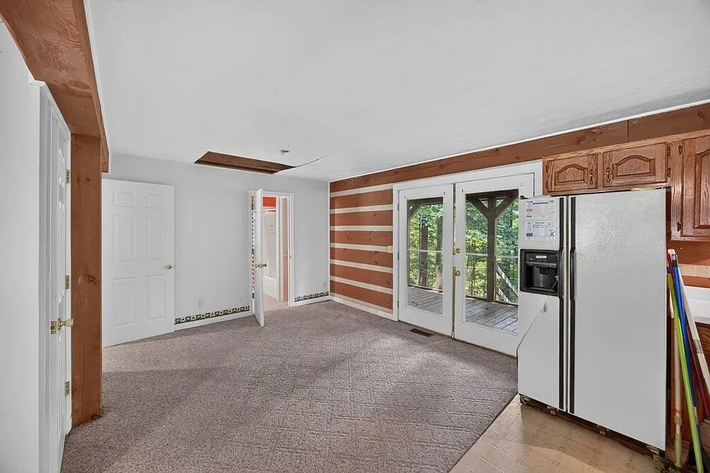 An open room with log walls and french doors leading outside
