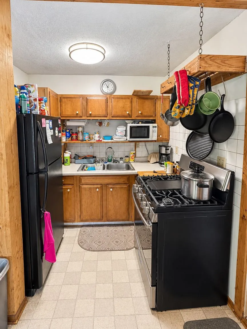 The kitchen with the oak cabinets, the black refrigerator and the range