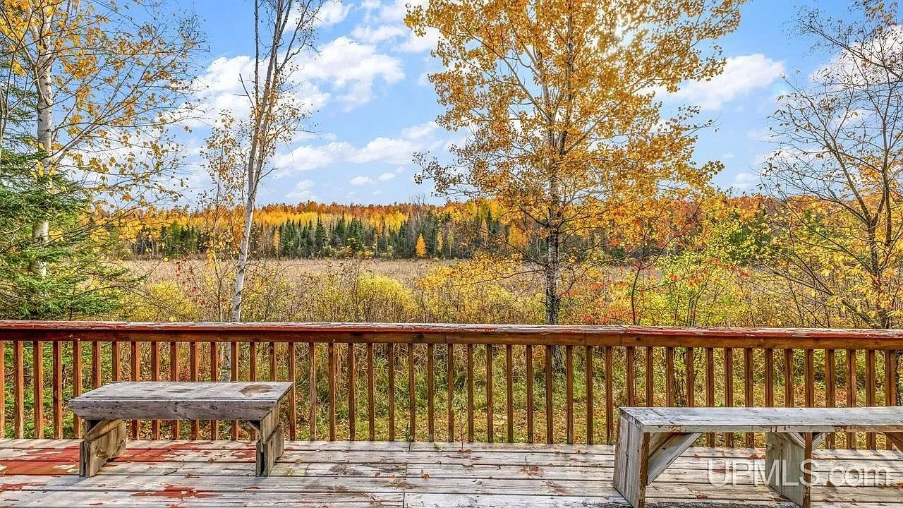 The deck railing with a view across an open meadow in fall color