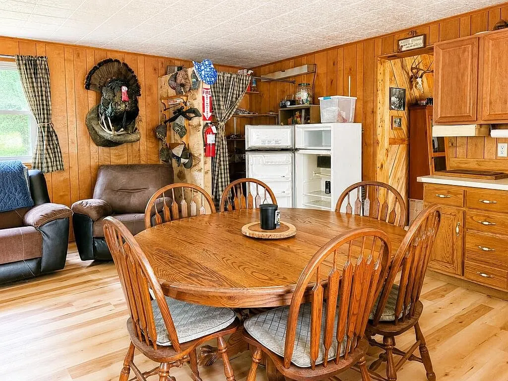 The oak dining table by the kitchen and the refrigerator