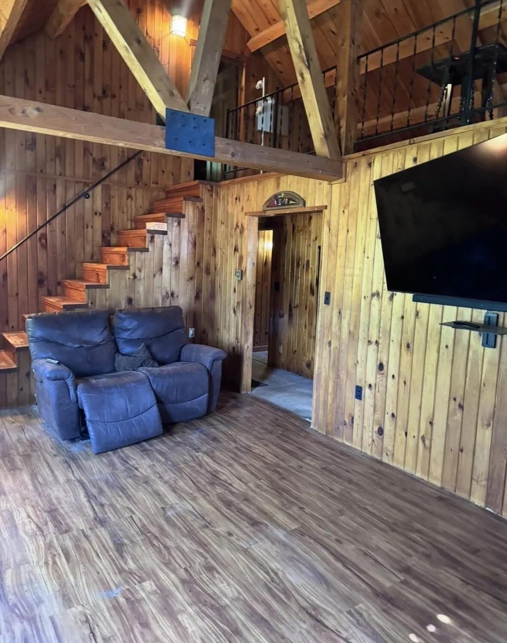 The living room with the stair to the loft, the recliner sofa and the television