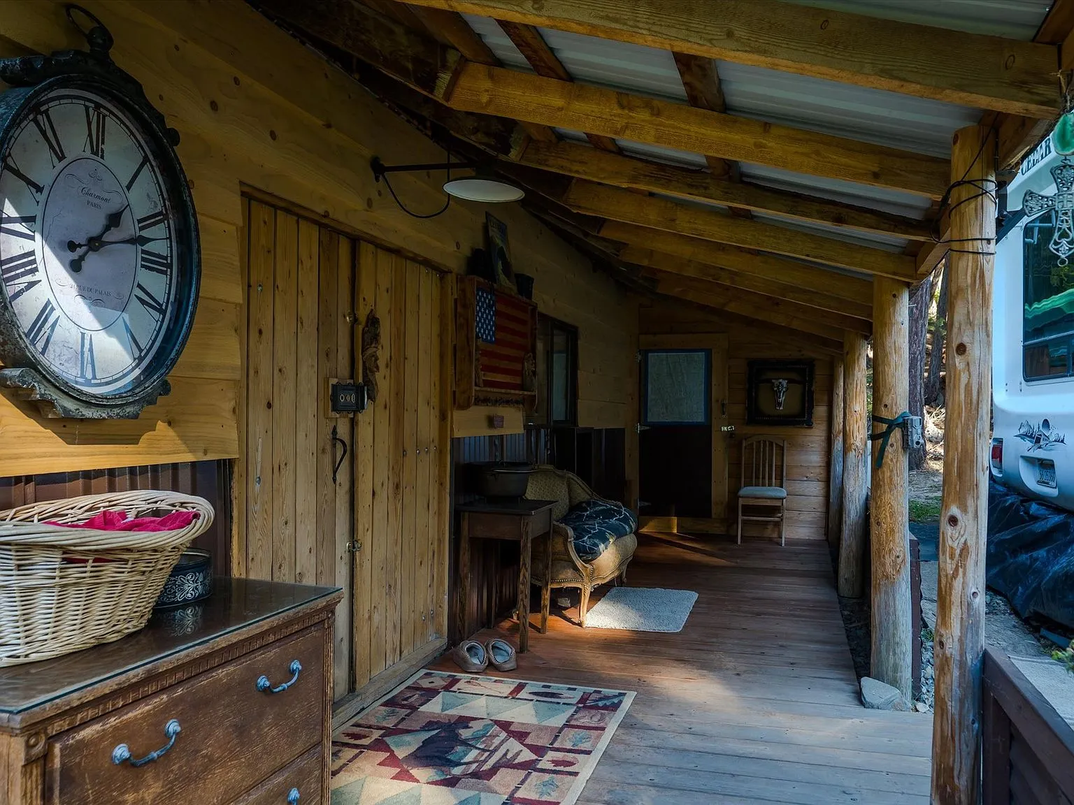 A second porch view with patio seating and a wagon-wheel planter in the yard