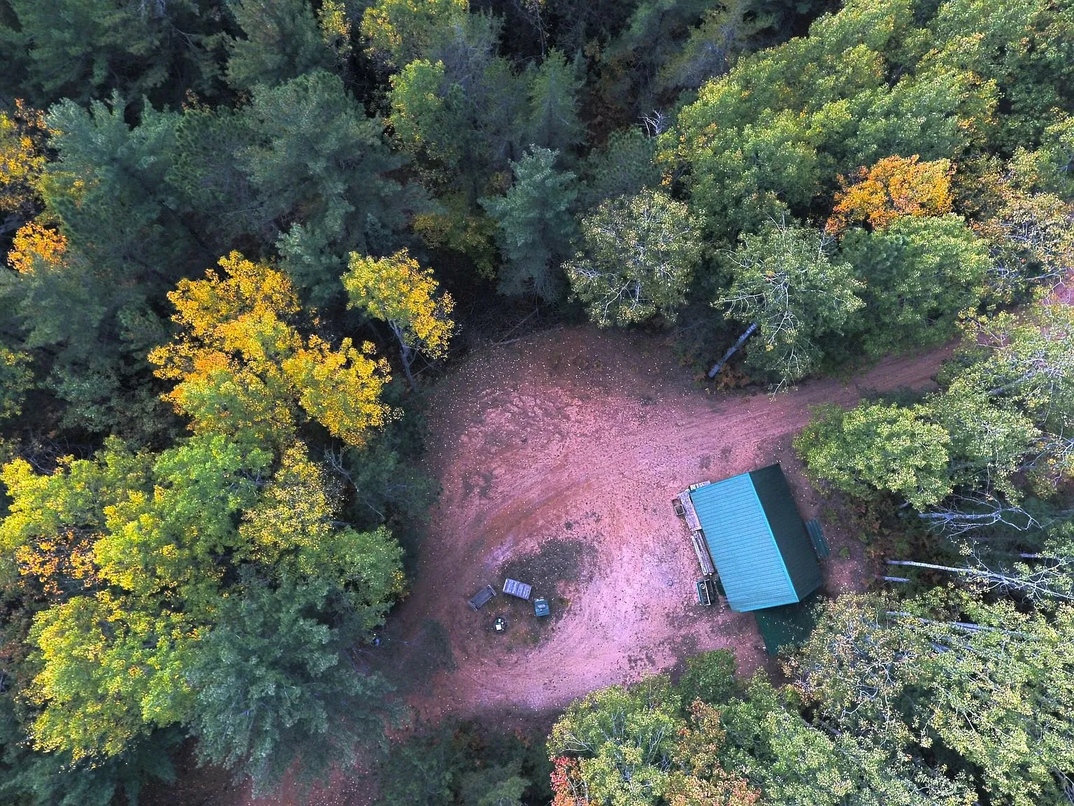 Aerial of the clearing from higher up, the drive cutting in through the trees