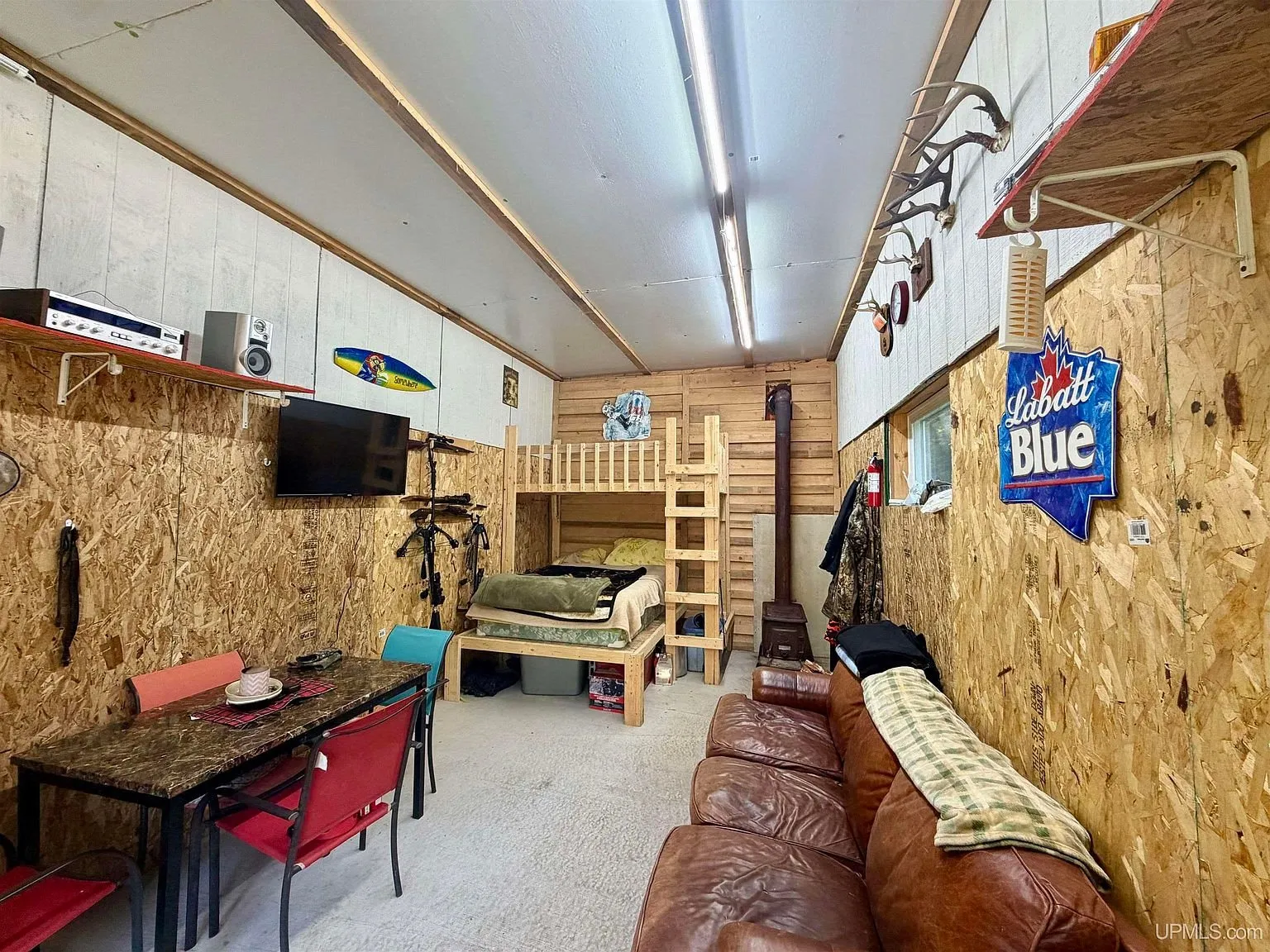 The bunk beds in the base camp with the stove pipe and the television