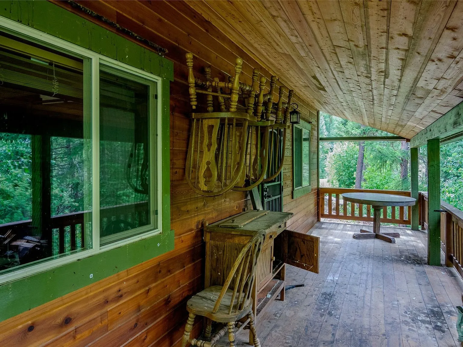 A covered porch with green trim, built-in bench seating and tool hooks