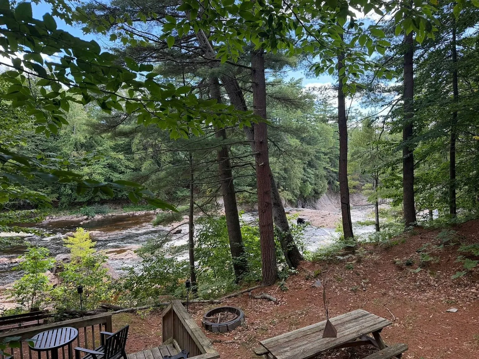 The picnic table and the fire ring on the bank with the river beyond