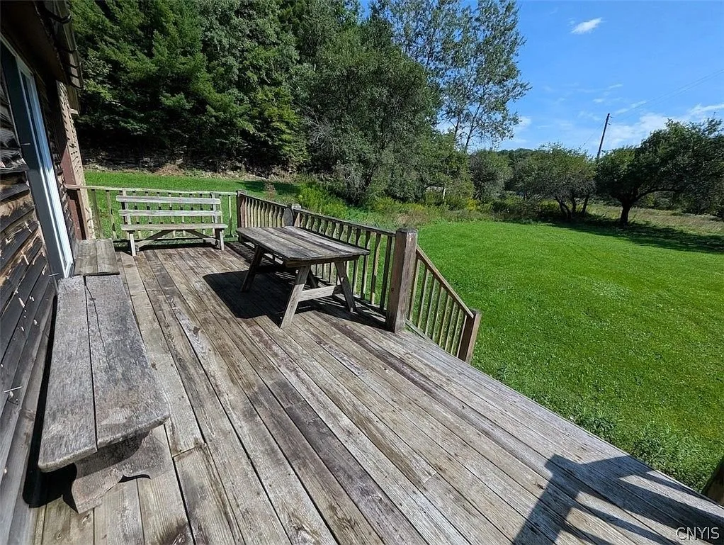 The deck with a bench and a table looking over the lawn