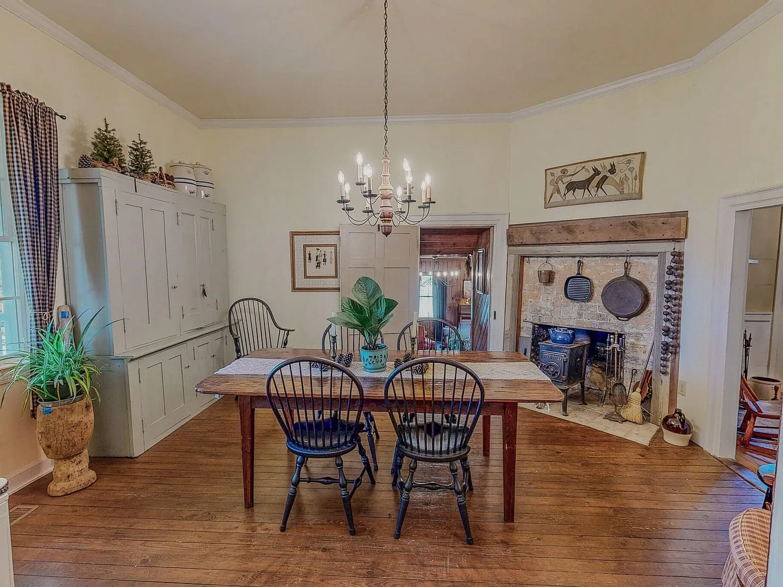 The dining room with a long wood table, Windsor chairs and a corner fireplace