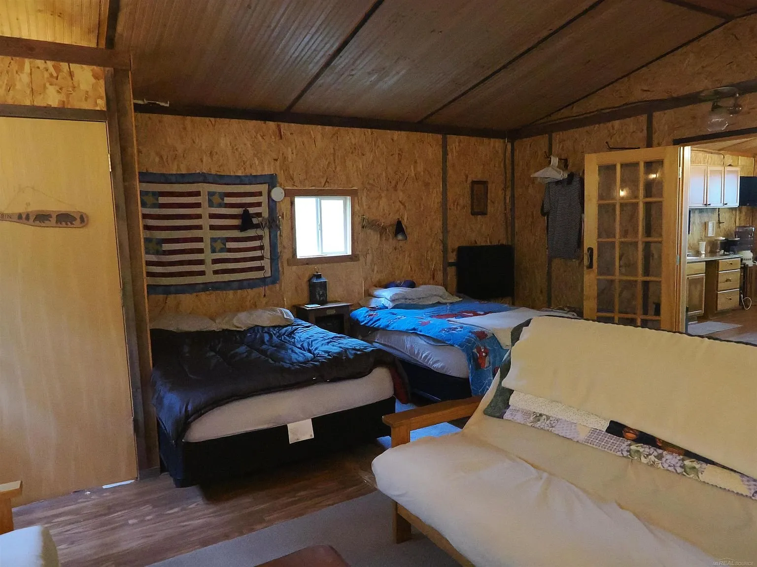 The bunk room with two beds, the flag on the wall and the french doors